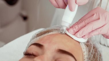 Sağlık merkezinde su mikro dermabrüksiyon tedavisi gören hasta kadın. Güzellik uzmanı yenilikçi bir cihaz kullanarak deriyi temizliyor ve tazeliyor. Susuzluk ve cilt yenilenmesini destekleyen gelişmiş bir prosedür.