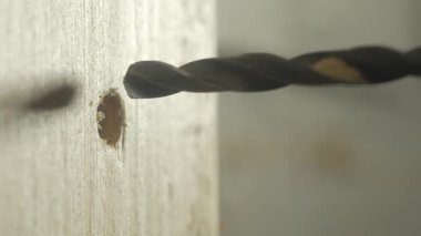 Tahtayı delip geçen elektrikli matkap temiz bir delik açıyor. Ev geliştirme ya da inşaat işi sırasında yan açı matkabı yüzeyi delip geçmiş. Güç aracı çalışıyor, kadrajda kimse yok