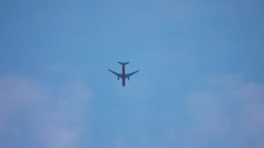 Bulutlu gökyüzünde uçan uçak. Jet uçağı ışık atmosferinde hareket ediyor. Yolcu uçağı yumuşak bulutların altında uçuyor. Mavi uzayda süzülen uçaklar