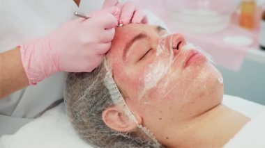 Güzellik kliniği kozmetoloji dolabında cilt bakımı gören bir kadın. Yetenekli eller profesyonel prosedürle kadın deri sağlığını geliştirmeye odaklanır. Kadın konforu tedavi sırasında öncelikli olarak belirlendi