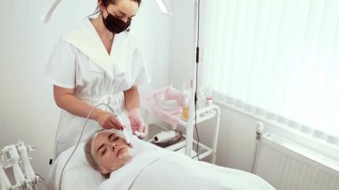 Kozmetik bilimci kozmetik atölyesinde ultrasonik temizlik aleti kullanıyor. Kadın uzman derin gözenek temizleme ve deri yüzme tedavisi uyguluyor. Bayan Güzellik Uzmanı müşteri için pürüzsüz ve tazelenmiş cilt garantisi veriyor