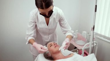 Kozmetik kliniğindeki olgun ciltleri gençleştirme terapisi parlaklığı arttırıyor. Uzman, müşterinin su ve esnekliğini arttırmak için özenle tedavi ediyor. Terapist ince çizgilerin azaltılmasına odaklanarak cildin daha pürüzsüz ve sağlıklı olmasını sağlıyor.