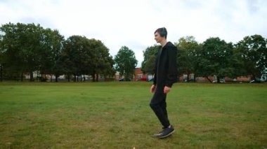 İngiltere 'de parkta kulaklıkla yürüyen bir genç. Genç adam İngiltere 'de çim üzerinde müzik dinliyor. İngiltere 'de parkta kulaklıkla dolaşan bir çocuk. İngiliz parkında kulaklık takan genç bir erkek.