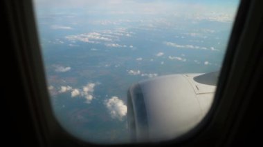Uçak Türbini İniş sırasında Sisli Koşullar içinde Uçarken Geçit 'ten Görünür. Pencerenin yanında türbin ve kanatlar var. Kabarık beyaz bulutların üzerinden geçen uçak