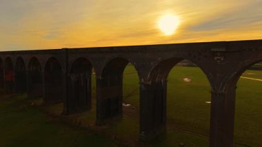 İngiliz demiryolu viyaolkü canlı akşam gökyüzüne karşı duruyor. Resimli vadi boyunca uzanan tarihi viyadük manzarası. Tarihi yerler, ünlü bölge, manzaralı manzaraları aşan ulaşım yapısı