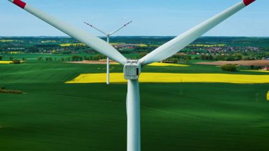 Dönen rüzgar türbini rotoru yakın planda temiz elektrik üretiyor. Dönen rüzgar jeneratörü yeşil alanlar üzerinde yenilenebilir güç üretiyor. Yel değirmenini döndürmek renkli kırsal bölgelerde sürdürülebilir enerji yaratıyor