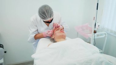 Kız yüzünde pigmentasyon sorunlarıyla ilgilenen bir kadın. Dermatolojik işlemler yapan profesyonel bir kadın. Cilt renginin ve sağlığının iyileştirilmesi için kozmetoloji tedavisi gören kız