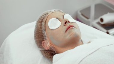 Kadın müşteri deri stüdyosunda profesyonel tedavi sırasında dinleniyor. Dişi, cilt dokusunu geliştirmek için yüz terapisini yeniliyor. Lüks ortam konfor sağlar.