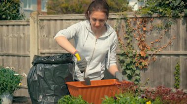 Bahçe işleri sırasında ekiciyi toprakla dolduran bir kadın. Bir kadın çiçek konteynırını hazırlarken aynı zamanda hobi ve sağlıklı yaşam tarzının tadını çıkarıyor. Bitkilerin büyümesini ve mevsimsel açık hava aktivitelerini desteklemek için toprak toplayan bir kadın.