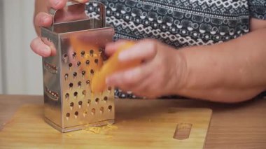 Ukrayna çorbası pişirmek için metal öğütücüde rendelenmiş havuç. Geleneksel çorba hazırlamak için turuncu sebzeyi rendeleyiciye sürtmek. Borş tarifi yapmak için taze havuç öğütüyorum. Kök bileşeni sağlıklı yemek için ince parçalar halinde işleniyor.