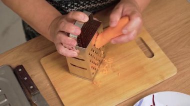 Metal öğütücüde öğütülmüş havuç Ukrayna borşunu hazırlıyor. Ukrayna 'nın ulusal çorbası için taze sebze kökü ovuyorum. Turuncu havucu öğütmek geleneksel Slav tarifi için bileşen oluşturuyor