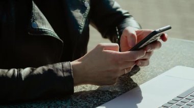 Cep telefonu tutan ve dışarıdaki sosyal medya içeriğini kaydıran kadın eller. Bilgisayarın yanındaki akıllı telefondan dijital ağa bakan bir kadın. Açık hava çalışma alanında mobil cihaz kullanan tanınmayan kişi. Taşın başında otururken uzak kullanıcı güncellemeleri kontrol ediyor