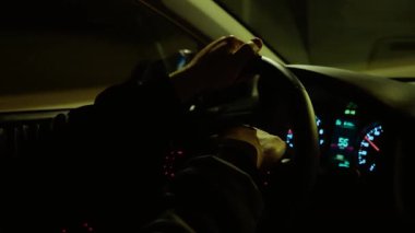 El sıkışan direksiyon, tanınmayan bir adam sokak lambalarının altında araba kullanırken. Erkek direksiyon, yanan otoyol boyunca tekerlek tutuyor. Gece otobanında araba sürmek, parlak yol lambalarının altında gezinmek.