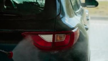 Otomatik yıkamada arabanın arka lambasına su sıkmak arka lambayı yüksek basınçlı hava akımıyla çalkalamak. Arka lambayı basınçlı su jeti kullanarak temizliyorum.