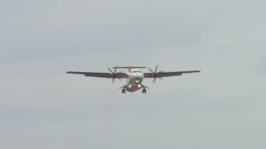 Pervane uçağı iniş pistine yaklaşıyor. Teçhizatlar kapalı ve ışıklar açık. Hava bulutlu koşullarda yavaşça alçalıyor. Bulutlu gökyüzünün altında görülebilir türbülansla sabit iniş.