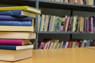 Kütüphanedeki ahşap masada yığınla kitap.