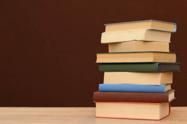 Siyah arkaplana karşı ahşap masadaki kitap yığını