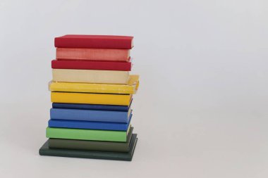 Beyaz bir arka plan üzerinde renkli kitap yığını.