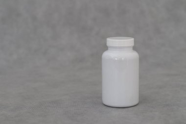 Gri arka planda cam kavanozda beyaz haplar..