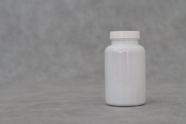 white plastic bottle with a jar of pills on a gray background.