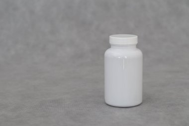 Gri arka planda cam kavanozda beyaz haplar..