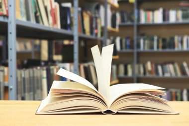 Tahta masanın üzerinde kitaplar olan açık bir kitap.