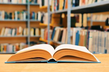 Kütüphanedeki ahşap masada yığınla kitap.