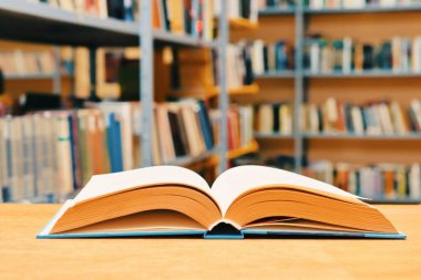 Kütüphanedeki ahşap masada yığınla kitap.