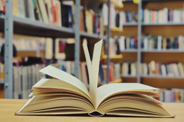 Kütüphanedeki ahşap masada yığınla kitap.