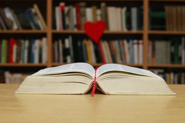 red book with hearts on wooden table in library background, valentines day and love concept