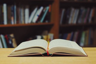 Kütüphanedeki ahşap masada yığınla kitap.