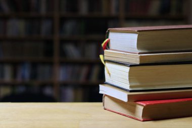 Kütüphanedeki ahşap masada yığınla kitap.