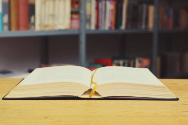 Kütüphanedeki ahşap masanın üzerinde açık bir kitap