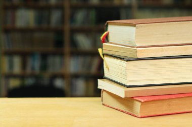 Kütüphanedeki ahşap masada yığınla kitap.