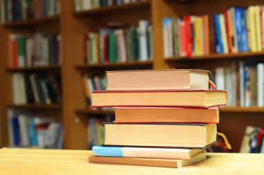 Kütüphanedeki ahşap masada yığınla kitap.