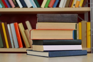 Kütüphanedeki ahşap masada yığınla kitap.