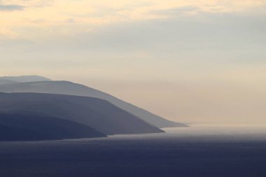 Denizde gün batımı. Ufuktaki adalar denizle çevrili.