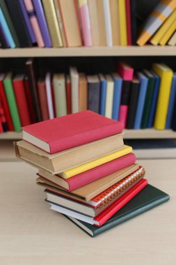 Odanın ahşap masasında bir yığın farklı renkli kitap.