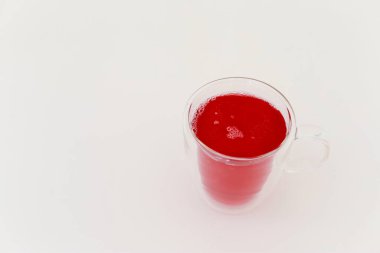 red juice in a glass on a white background.