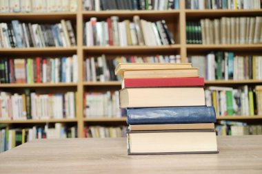 Kütüphanedeki ahşap raflarda yığınla kitap.