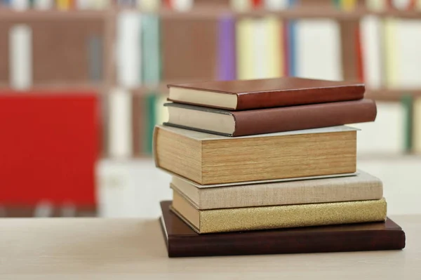 books on wooden desk in library, blurred background.