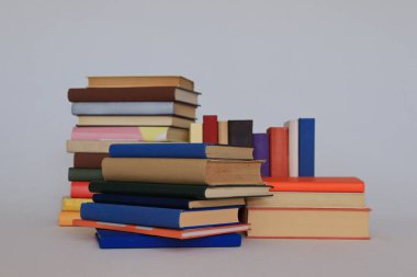 Beyaz arkaplan üzerine kitap yığını şeklinde renkli kitaplar yığını.