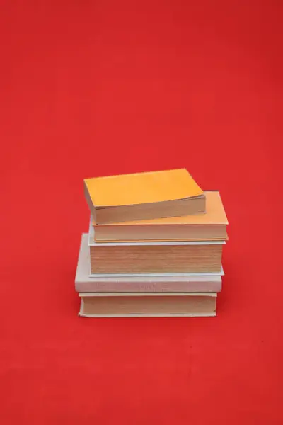 red stack of books on orange background.