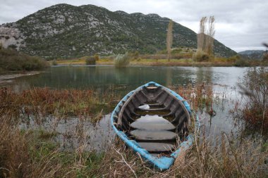 Arka planda dağlar ve tekneler olan göl.