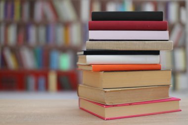 Kütüphanedeki ahşap masada yığınla kitap.