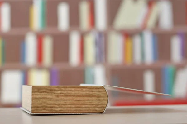 wooden book in the library on blurred background, closeup. space for text