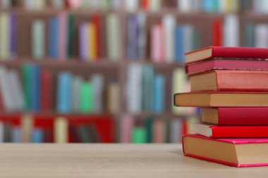 Kütüphanedeki ahşap masada kitap yığını var.