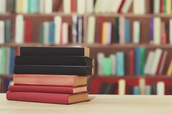 Kütüphanedeki ahşap masada yığınla kitap.