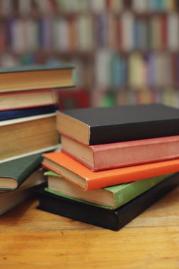 Kütüphanedeki ahşap masada yığınla kitap.