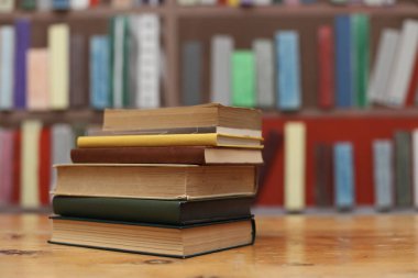 Bulanık arka plana karşı ahşap masadaki kitap yığını
